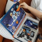 Child engaged in assembling a colorful space-themed puzzle indoors.